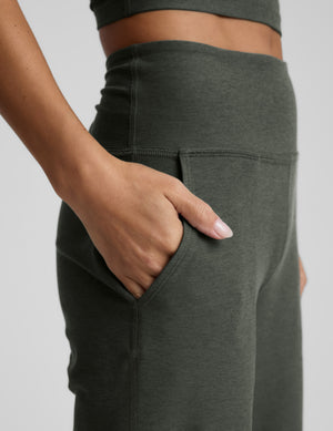 Close-up of green wide leg pants with pockets on a plain background. 