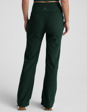 model wearing dark green high-waisted wide leg pants with pockets on a plain background. 