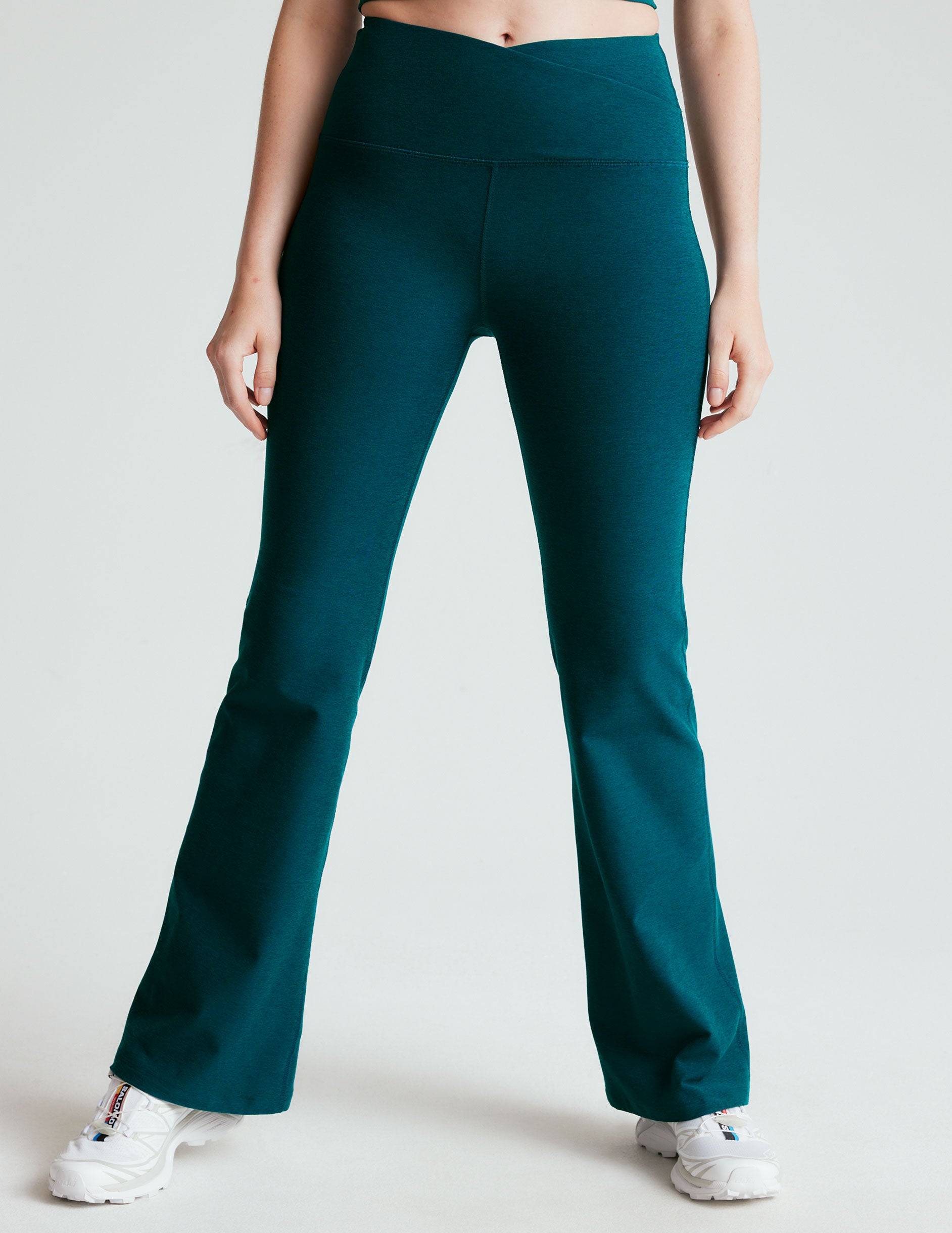 blue high-waisted bootcut pants with a front crossover detail on the waistband. 