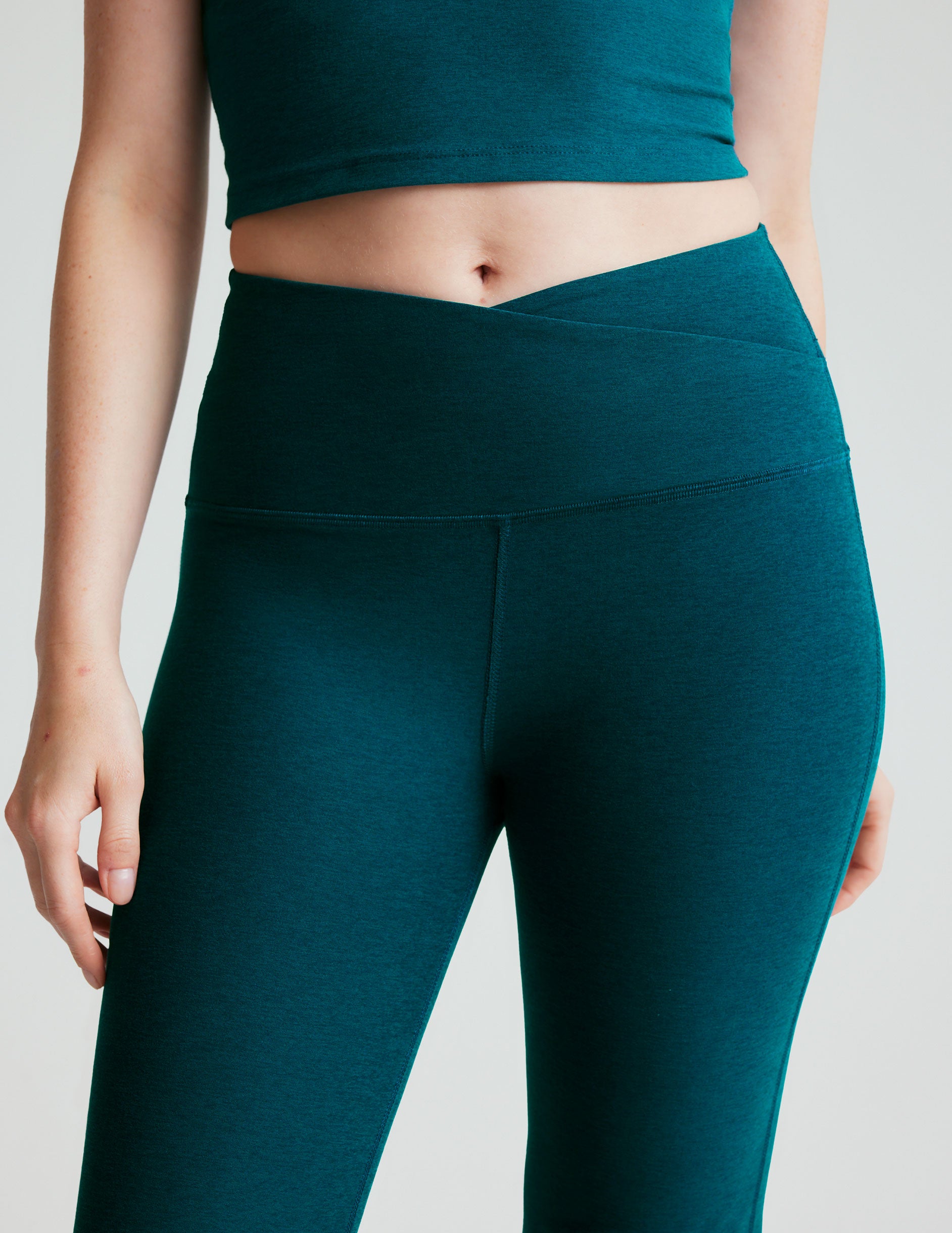 blue high-waisted bootcut pants with a front crossover detail on the waistband. 