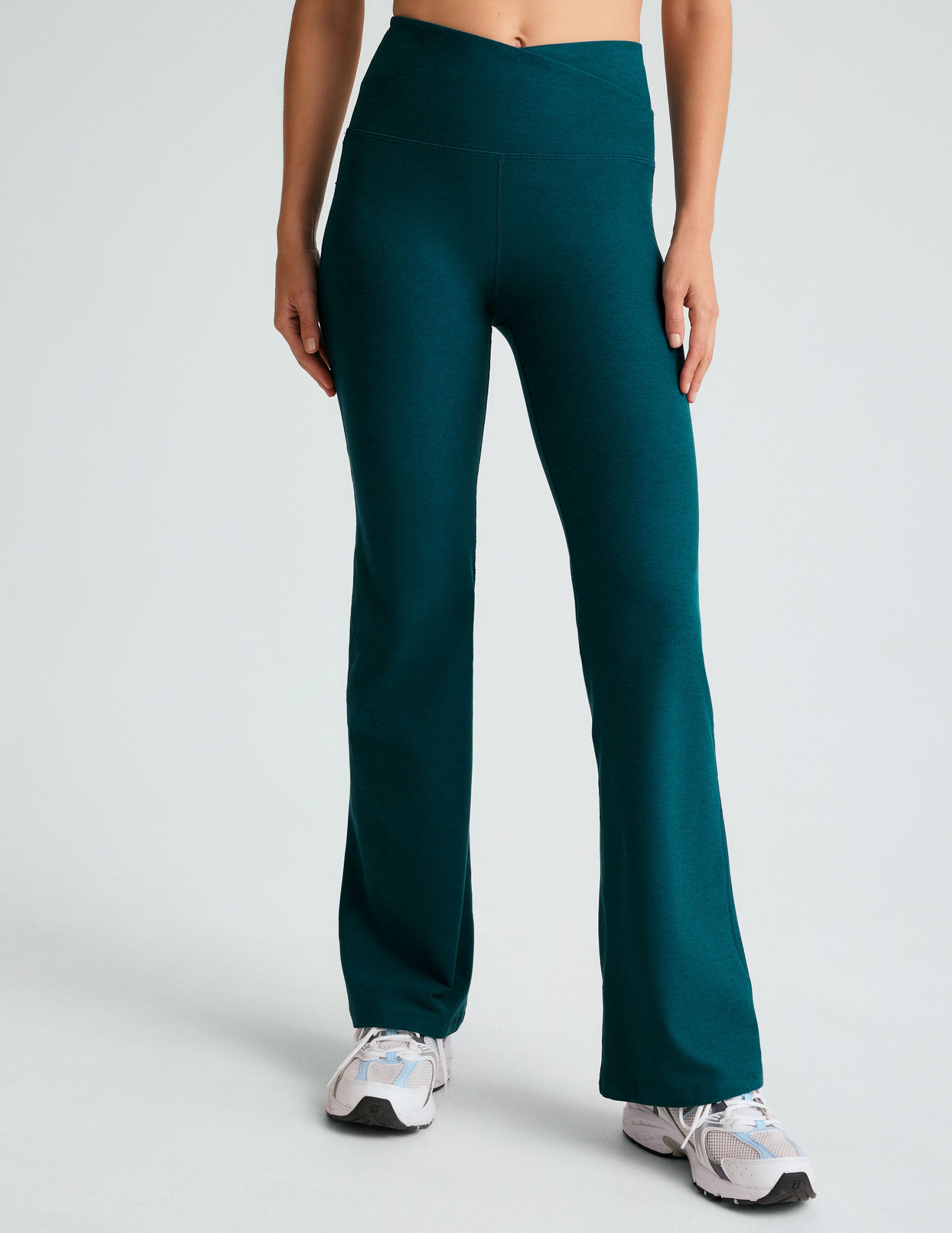 blue high-waisted bootcut pants with a front crossover detail on the waistband. 