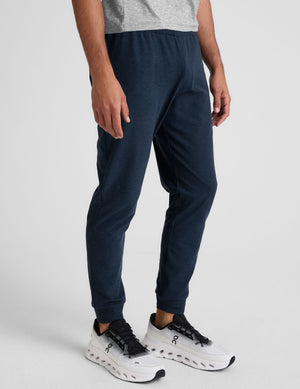 grey t-shirt and navy jogger pants on a plain background. 