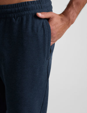 grey t-shirt and navy jogger pants on a plain background. 