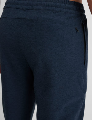 grey t-shirt and navy jogger pants on a plain background. 