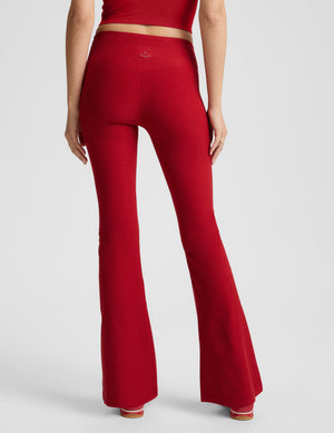 Woman wearing red mid-rise bootcut pants on a light gray background. 