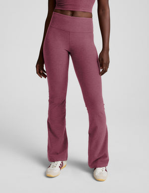 Person wearing purple mid-rise bootcut pants with a plain background. 