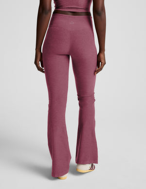 Person wearing purple mid-rise bootcut pants with a plain background. 