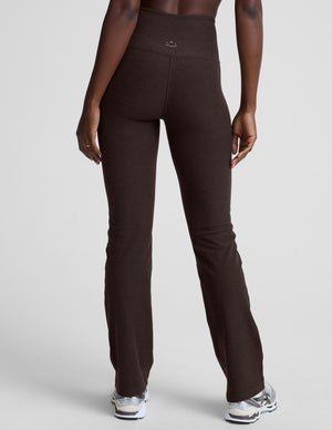 woman wearing a brown sports bra and mid-rise pants on a white background. 