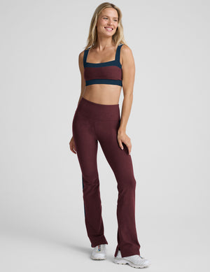 model wearing burgundy pants with a blue stripe on a light gray background. 
