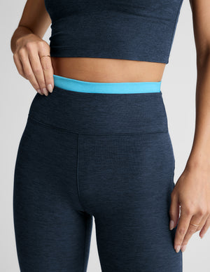 Woman wearing a navy athletic outfit with a white background. 