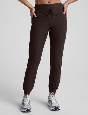 woman wearing a brown joggers with pockets on a light gray background. 