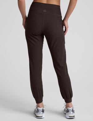 woman wearing a brown joggers with pockets on a light gray background. 