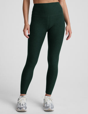 model wearing green high-waisted full length leggings on a plain background. 