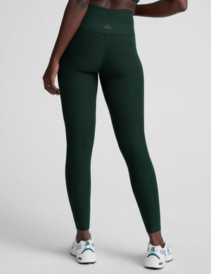 model wearing green high-waisted full length leggings on a plain background. 