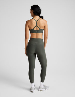 Woman wearing a green sports bra and leggings set on a white background. 