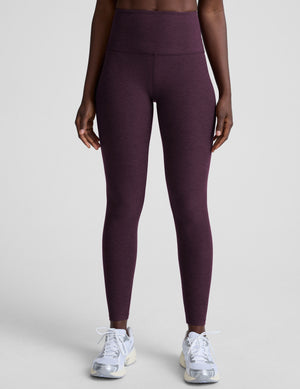 model wearing purple high-waisted midi length leggings  on a light background. 