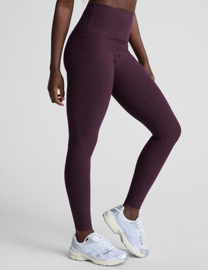 model wearing purple high-waisted midi length leggings  on a light background. 