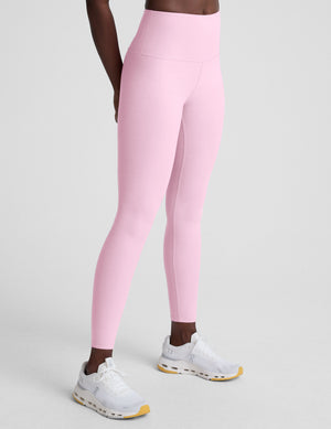 Person wearing pink leggings on a plain background. 