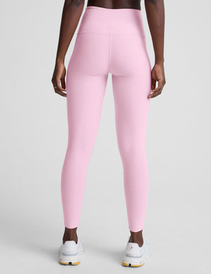 Person wearing pink leggings on a plain background. 