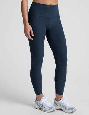 navy blue high-waisted midi leggings worn by model on a light gray background. 