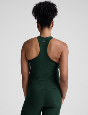 model wearing a green maternity racerback tank and green maternity midi length leggings on a plain background. 