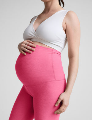 Woman wearing a white maternity bra and leggings against a plain background. 