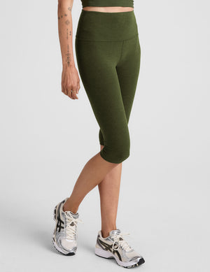 model is wearing green high-waisted pedal pusher length leggings. 