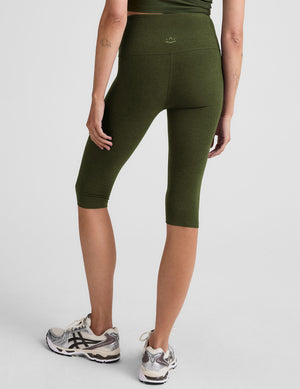 model is wearing green high-waisted pedal pusher length leggings. 