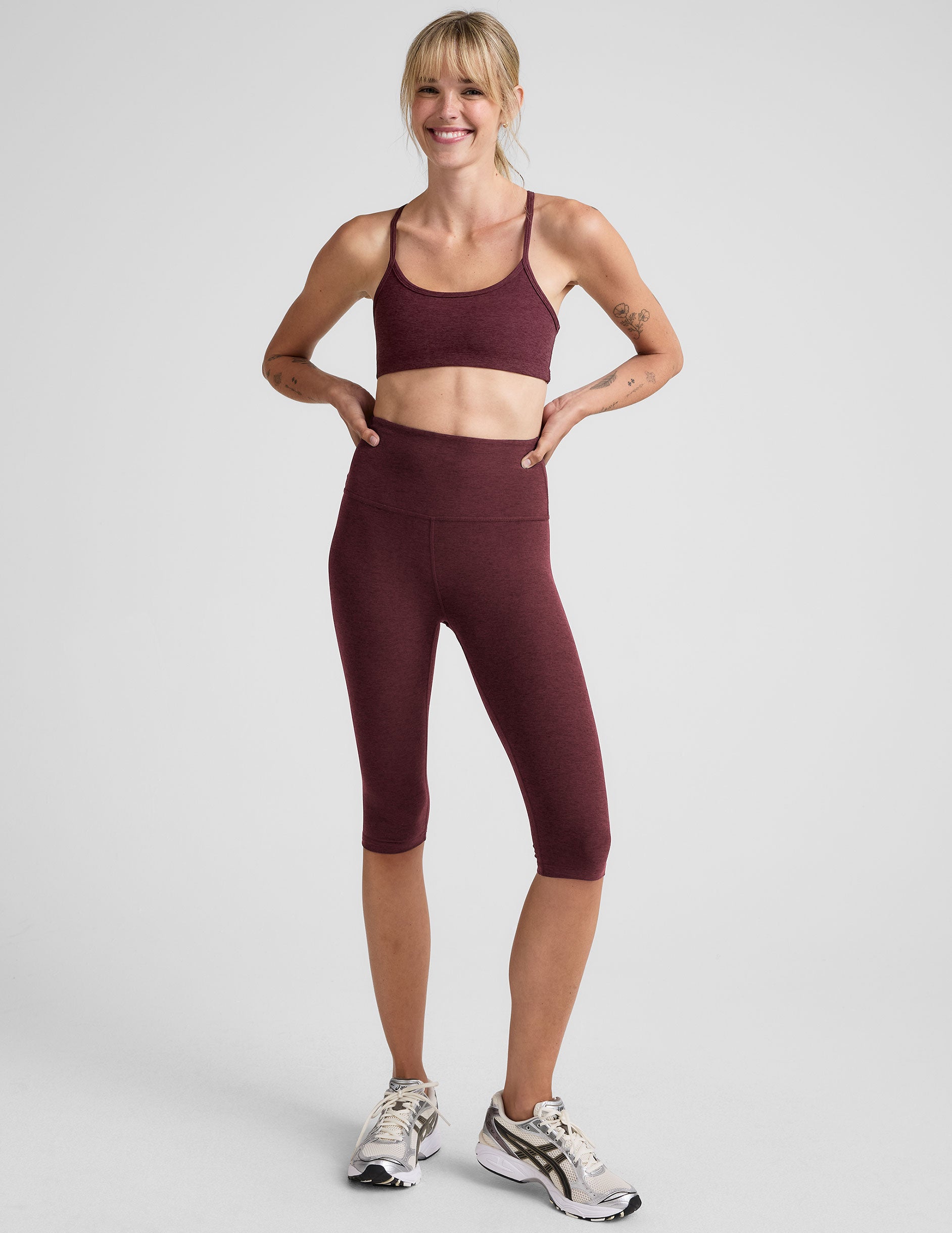 model is wearing red high-waisted pedal pusher length leggings. 