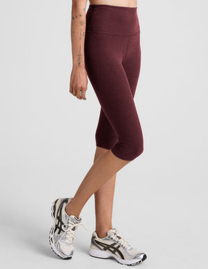 model is wearing red high-waisted pedal pusher length leggings. 