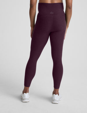 pregnant woman wearing maternity leggings with pockets against a plain background. 