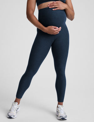 Person wearing navy leggings on a plain background. 