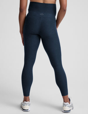 Person wearing navy leggings on a plain background. 