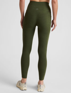 green high-waisted midi length leggings with side pockets on a plain background. 