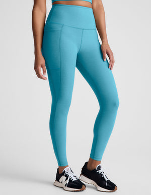 Person wearing blue leggings on a plain background. 