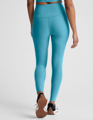 Person wearing blue leggings on a plain background. 