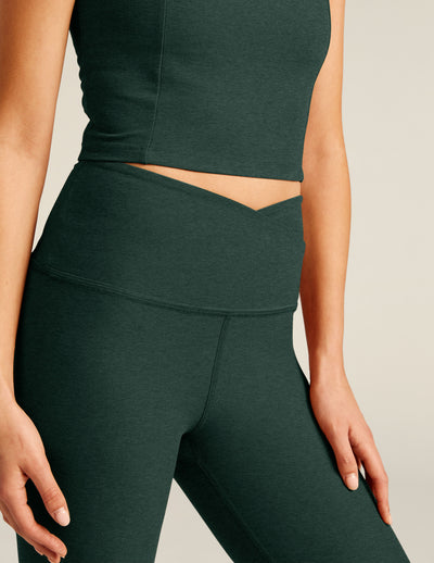 green high-waisted midi leggings with a crossover design on the front waistband. 