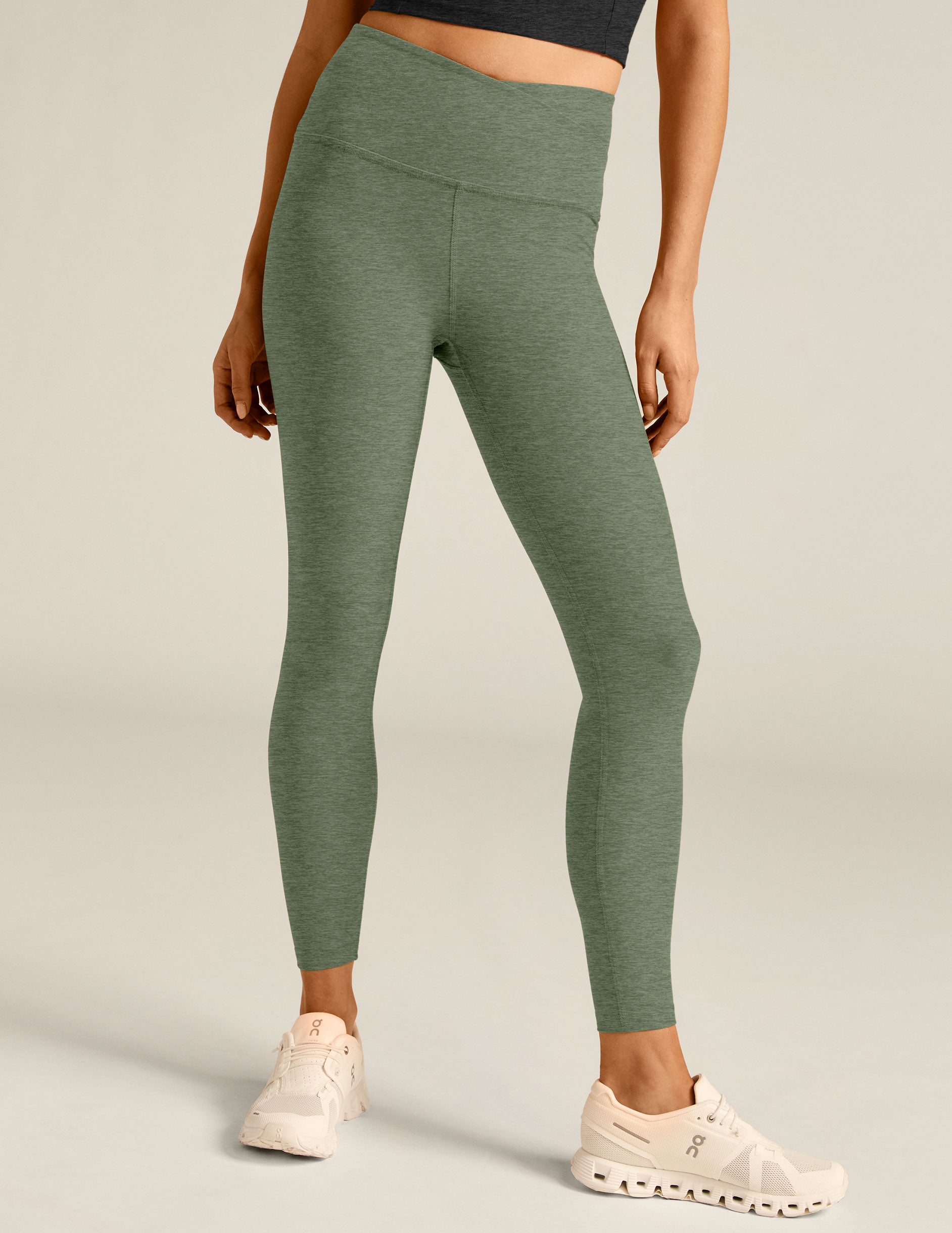 green high-waisted midi leggings with a crossover detail on the front waistband. 