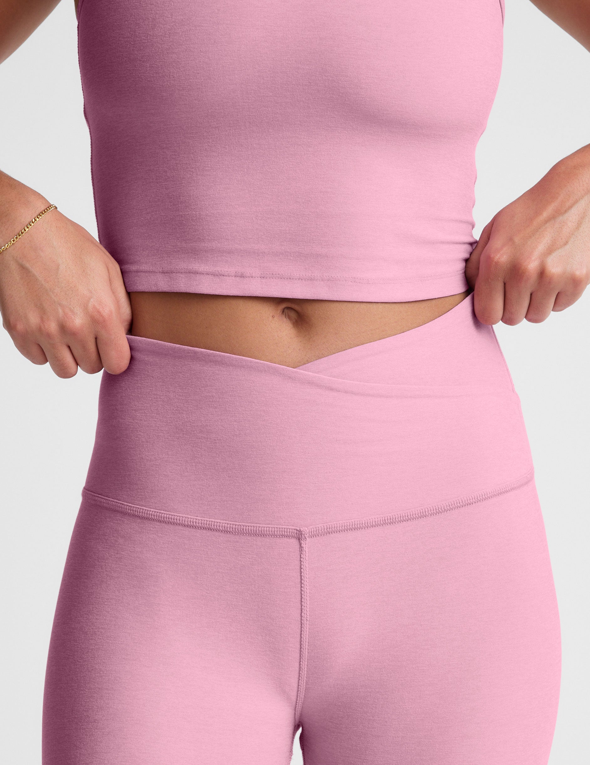 pink high-waisted midi leggings with a crossover detail on the front waistband. 