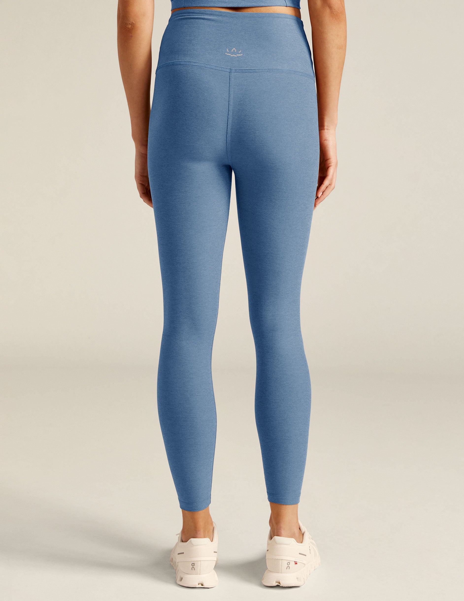 blue high-waisted midi leggings with an overlapping detail on the front waistband. 