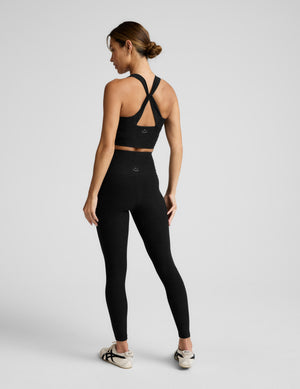 Woman wearing a black athletic outfit on a light gray background. 