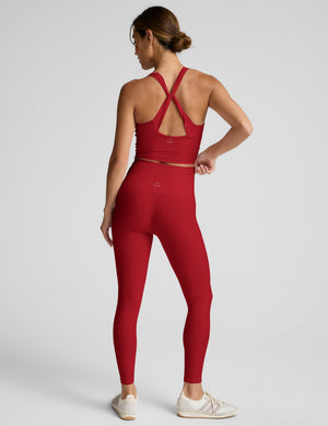 Woman wearing a red athletic outfit on a light gray background. 