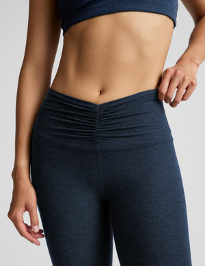 Person wearing navy blue athletic leggings on a light gray background. 