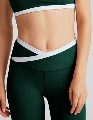 green high-waisted midi length legging with a crossover detail on the front waistband with white contrast binding along waistline. 
