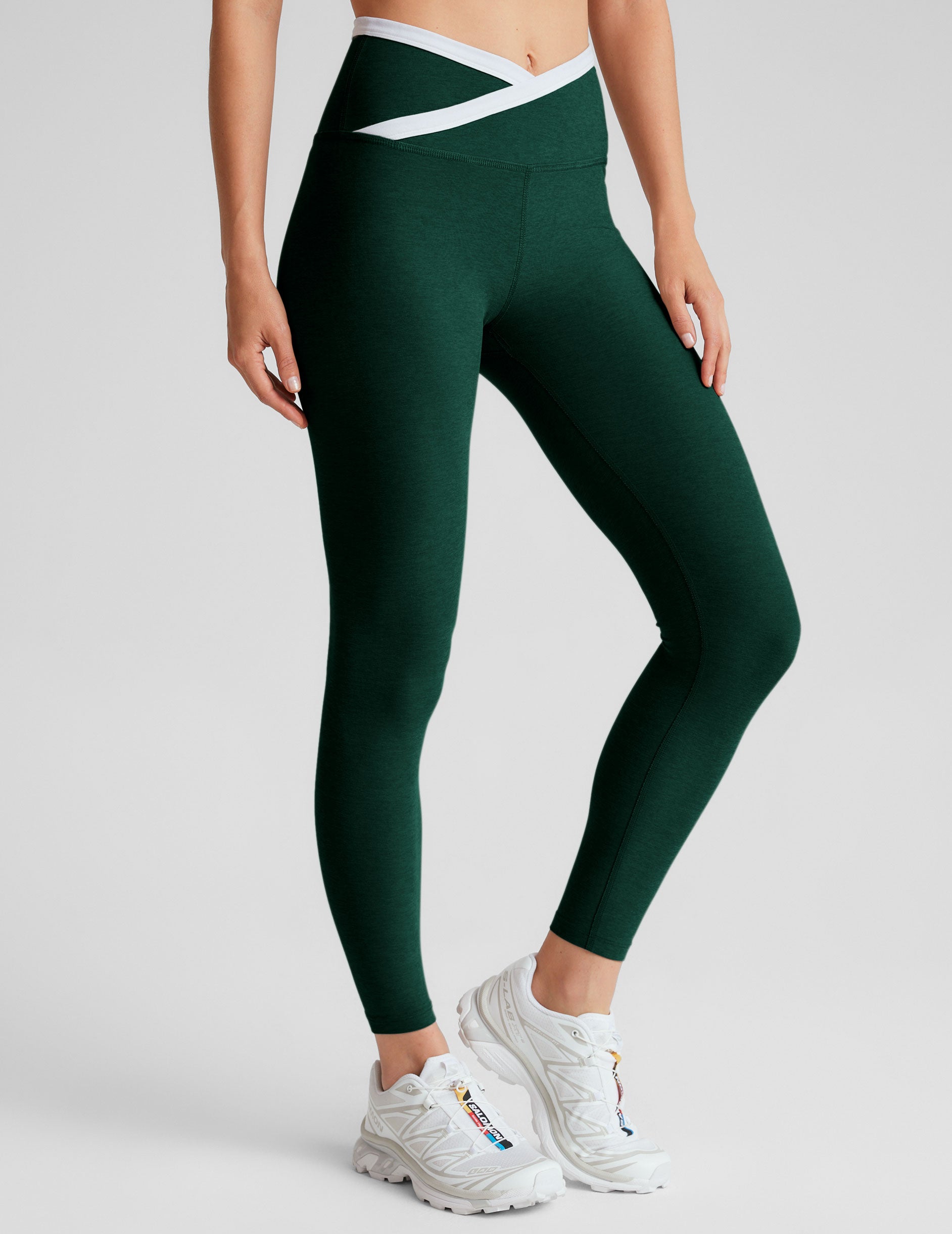 green high-waisted midi length legging with a crossover detail on the front waistband with white contrast binding along waistline. 