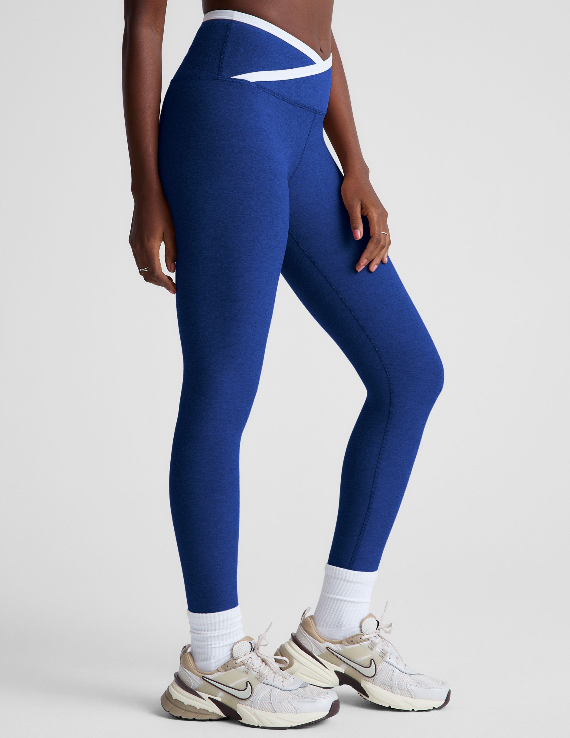 blue high-waisted midi length legging with a crossover detail on the front waistband with white contrast binding along waistline. 