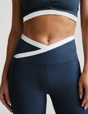 Woman wearing a navy sports bra and leggings set on a light gray background. 