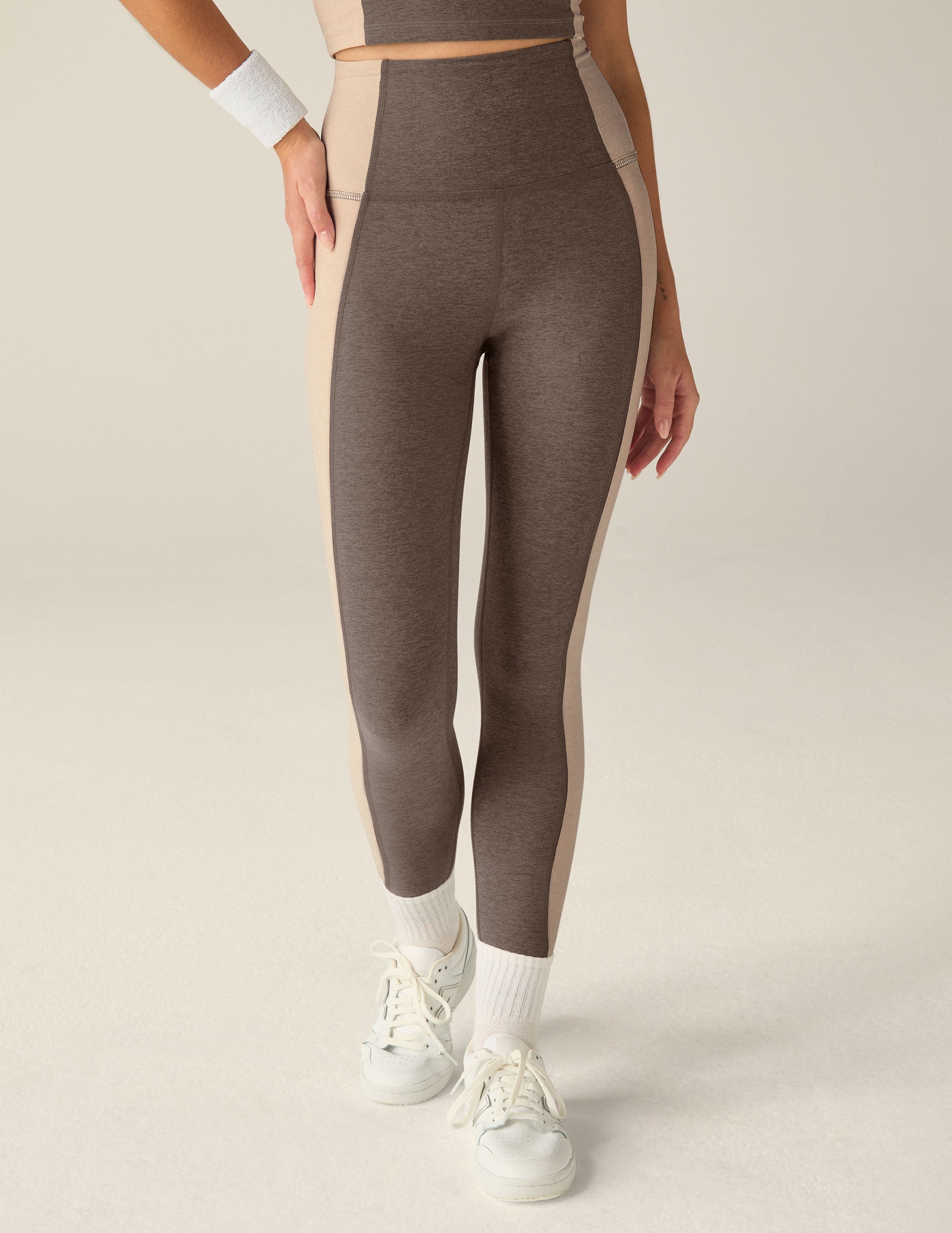 brown high-waisted midi leggings with eggshell outline details on the sides. 