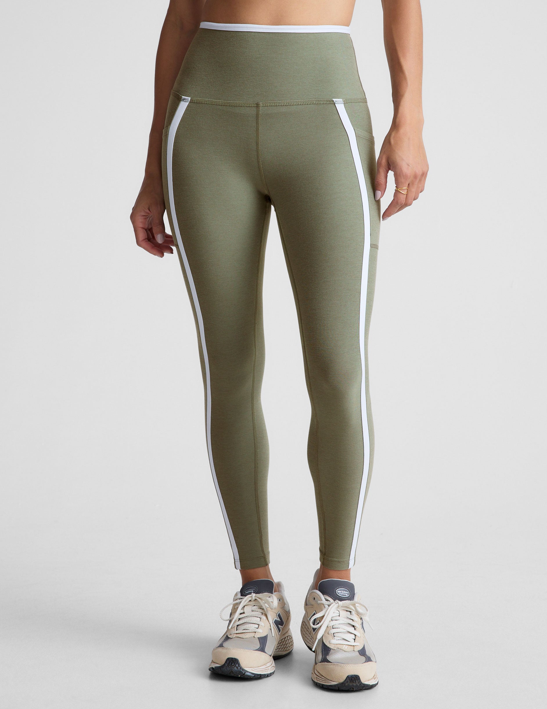 green high-waisted midi length legging with side pockets and white piping. 