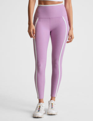 purple high-waisted midi length legging with pockets and white piping. 